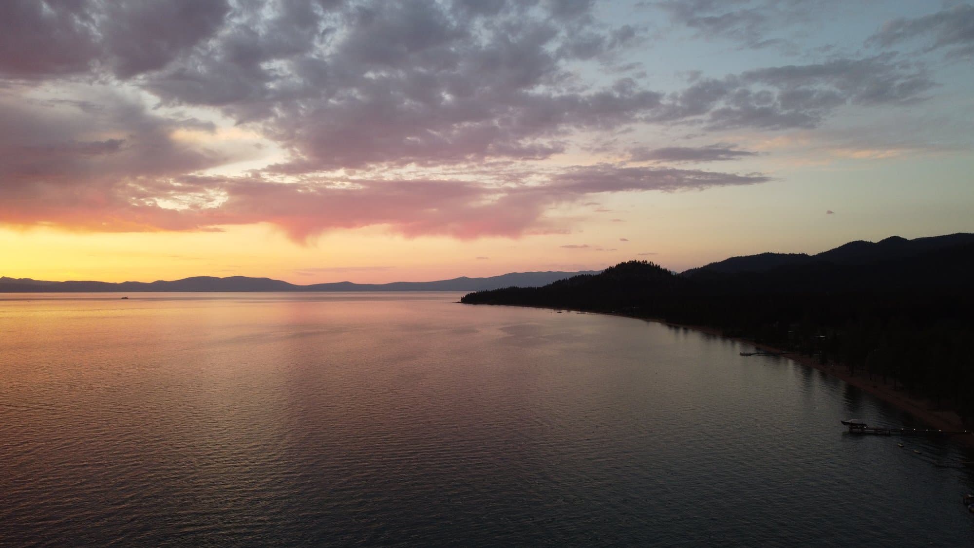 Coastal twilight, soft pink light over still water and dark mountains